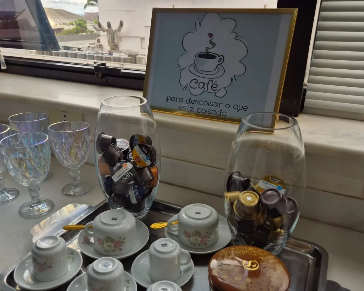 Cantinho do café da Clínica SINApsis, com xícaras servidas em bandeja junto à janela.