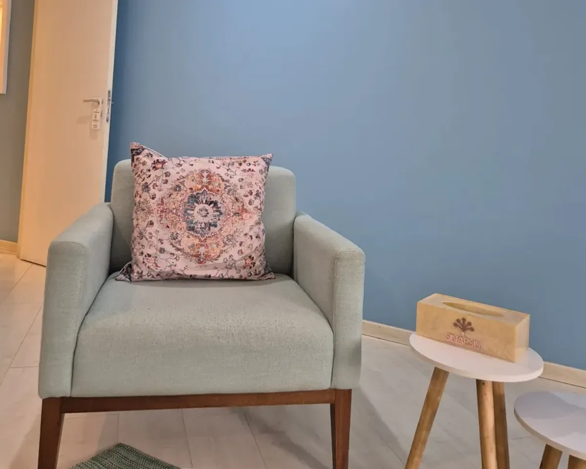 Poltrona de atendimento individual da Clínica SINApsis, na Asa Norte, diante da parede azul, com mesa de apoio ao lado.